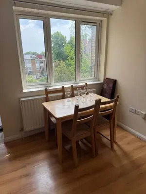 a dining room with a table and chairs and windows at Your Base To Explore London in Moffat