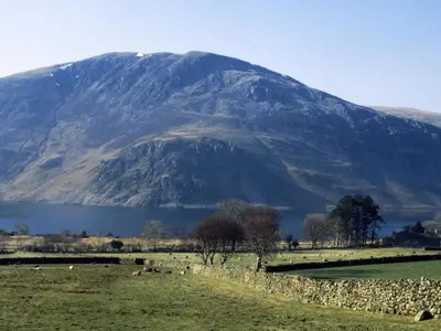 a mountain in the background of a field with sheep at Sycamore Cottage, Western Lakes Bolthole With Views Across the Fells in Arlecdon