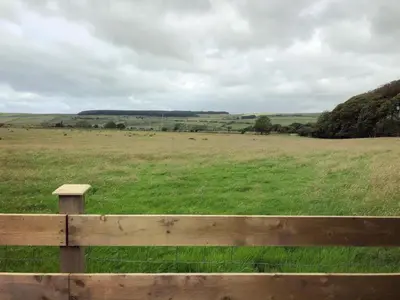 a wooden fence in a field with green grass at Sycamore Cottage, Western Lakes Bolthole With Views Across the Fells in Arlecdon