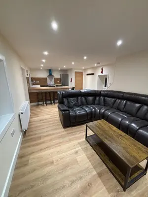 a living room with a black leather couch and a table at Ballavelt in Isle of Man