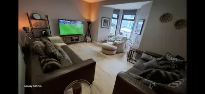a living room with a couch and a tv at Central Portrush Townhouse available for Open Golf in Moffat