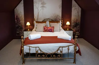 a bedroom with a large bed with two lamps at Our Cosy Cottage in Gatehouse of Fleet