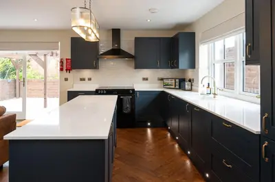 a kitchen with black cabinets and a white counter top at Our Cosy Cottage in Gatehouse of Fleet