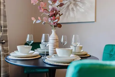 a dining room table with a vase with flowers and glasses at Welcoming Home in Hurlford, Kilmarnock - Bonnie Lodgings in Hurlford