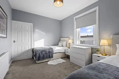 a bedroom with two beds and a window at Welcoming Home in Hurlford, Kilmarnock - Bonnie Lodgings in Hurlford
