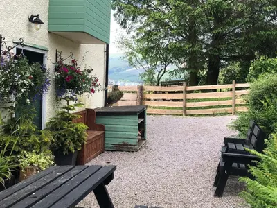 a garden with a wooden bench and a fence at Corlae Cottage, mountain and forest views in Carsphairn