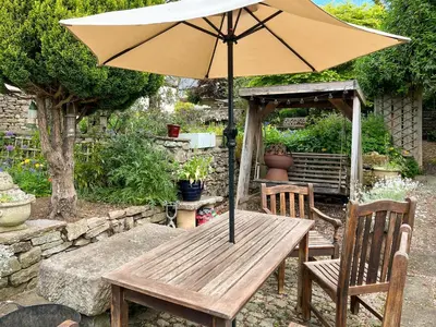 a wooden table with an umbrella and two chairs at Cottage At Brathen in Penrith