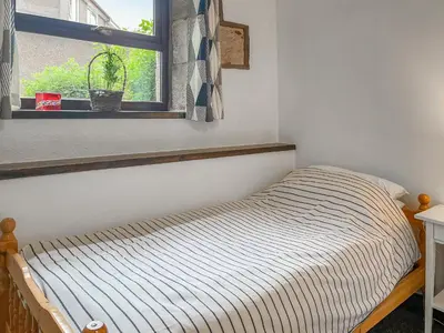 a bed sitting in a room with a window at Cottage At Brathen in Penrith