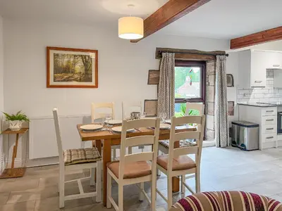a kitchen and dining room with a wooden table and chairs at Cottage At Brathen in Penrith
