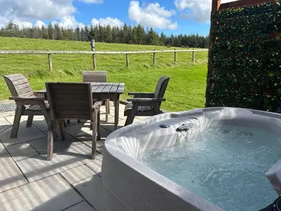 a jacuzzi tub with chairs and a table and a table and chairs at Barnharrow Holiday Pods - Rose Glamping Pod with Hot Tub & Fire Pit in Balminnoch