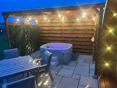 a bath tub sitting on a patio with a bench at Barnharrow Holiday Pods - Rose Glamping Pod with Hot Tub & Fire Pit in Balminnoch