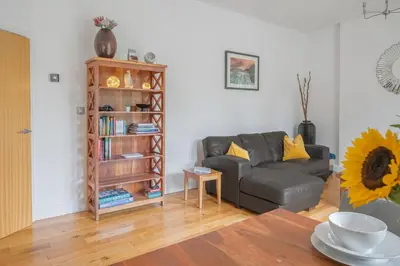 a living room with a couch and a book shelf at Chaucer Apartment in Keswick