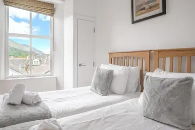 a bedroom with two beds and a window at Chaucer Apartment in Keswick
