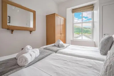 two white beds in a room with a window at Chaucer Apartment in Keswick