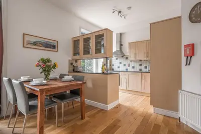 a kitchen and dining room with a wooden table and chairs at Chaucer Apartment in Keswick