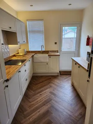 a kitchen with white cabinets and a wooden floor at The Troon Hoose in Troon
