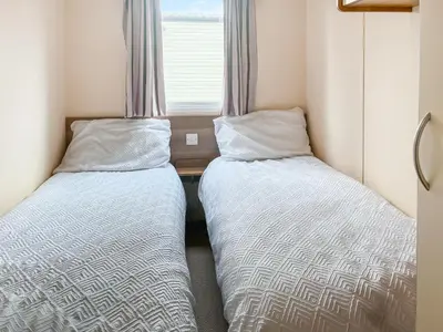 two beds in a small room with a window at Platinum in Newton Stewart