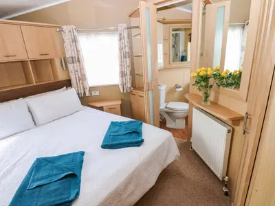 a bedroom with a bed with two blue towels on it at 12 Field View in Carlisle