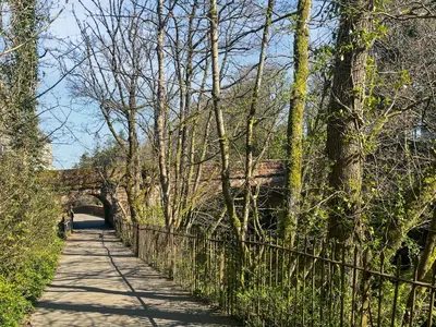 a fence next to a path with a bridge at Rubby Banks Retreat in Cockermouth