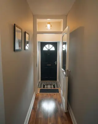 a hallway with a black door and a rug at Anchors Retreat in Ayr