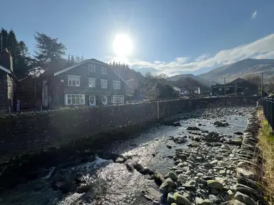 a river with rocks in front of a house at Swirral Edge Cottage in Penrith