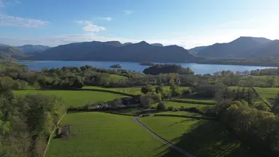 an aerial view of a green field and a lake at Castlehead Cottage in Keswick