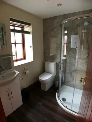a bathroom with a shower and a toilet and a sink at Castlehead Cottage in Keswick