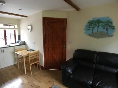 a living room with a black leather couch and a table at Castlehead Cottage in Keswick