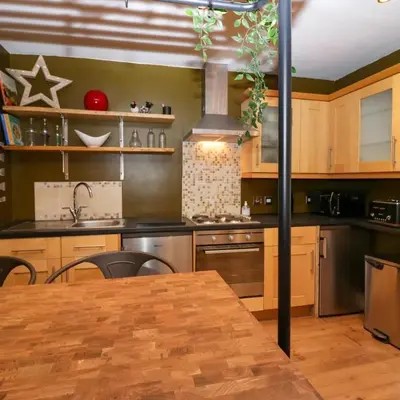 a kitchen with wooden cabinets and a wooden table at Tranquil Lake District Village Apartment in St Bees