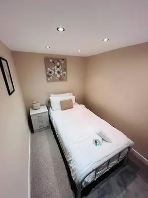 a bedroom with a large bed with white sheets at Abbeygreen Village House in Lesmahagow