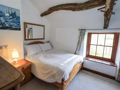 a small bedroom with a bed and a window at Chapel Cottage in Cleator