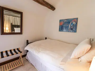 a bedroom with a white bed and a mirror at Chapel Cottage in Cleator