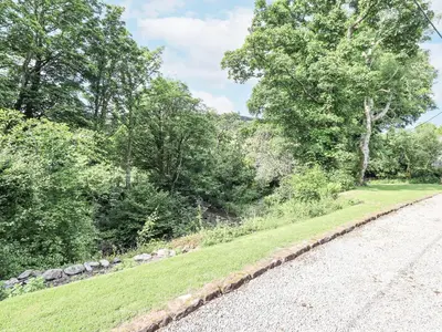 a road next to a field of grass and trees at Chapel Cottage in Cleator