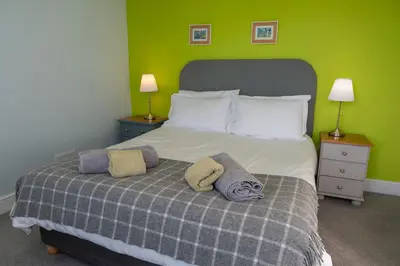 a bedroom with a bed with a green wall at Larroch Farmhouse in Monreith