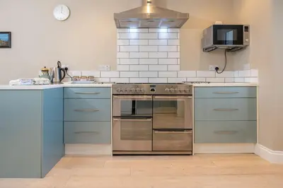a kitchen with blue cabinets and a stainless steel oven at Larroch Farmhouse in Monreith