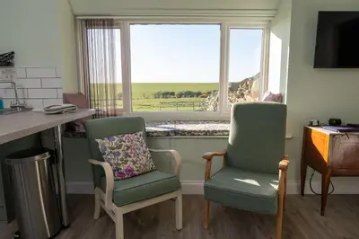 a kitchen with two chairs and a window at The Larroch Byre in Monreith