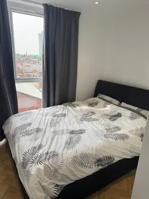 a bed with a black and white comforter and a window at Stylish Flat in City Center in Moffat