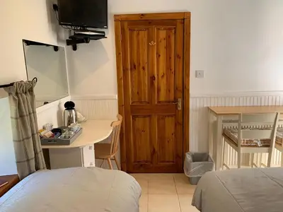 a bedroom with a desk and a door with a television at Whitestone Cottage in Turnberry