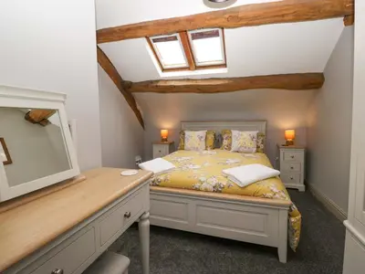 a bedroom with a bed with a desk and a tv at Yeat Stoup Cottage in Cockermouth