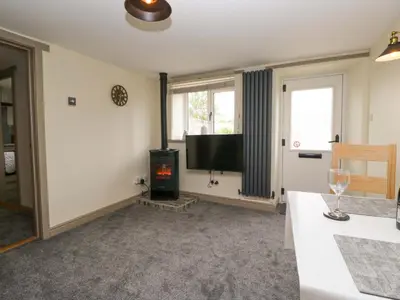 a living room with a flat screen tv and a stove at Yeat Stoup Cottage in Cockermouth