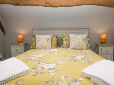 a bedroom with a yellow bed with two lamps at Yeat Stoup Cottage in Cockermouth