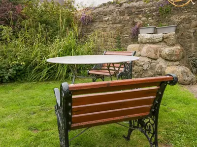 a table and a bench with a table and chairs at Yeat Stoup Cottage in Cockermouth