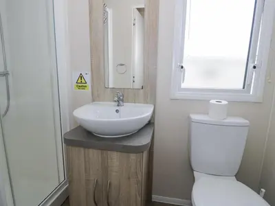 a bathroom with a sink and a toilet and a window at Manor House Gold 2 Bedroom 20C in Maryport