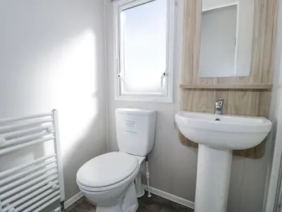 a bathroom with a toilet and a sink and a window at Manor House Platinum 3 Bedroom 16E in Maryport