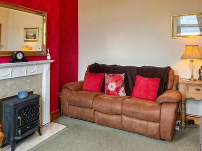 a living room with a brown leather couch with red pillows at The Haven in Annan