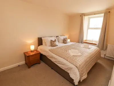 a bedroom with a large bed and a window at Sun House in Maryport