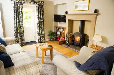 a living room with a fireplace and a couch at Charming cosy Lakeland cottage near Ullswater in Dacre