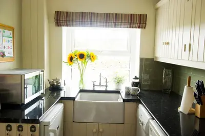 a kitchen with a sink and a window with sunflowers at Charming cosy Lakeland cottage near Ullswater in Dacre