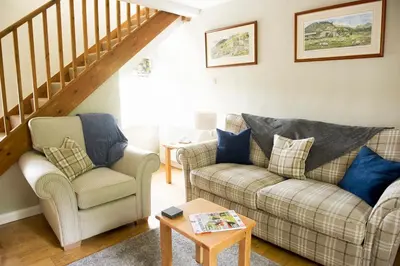 a living room with two couches and a staircase at Charming cosy Lakeland cottage near Ullswater in Dacre