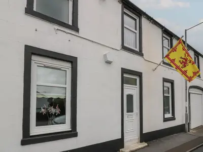 a white building with a window and a sign on it at King's Apartment in Castle Douglas